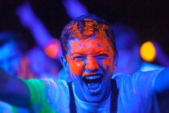 Performer firing a laser cannon into a glowing crowd at a GloZone party