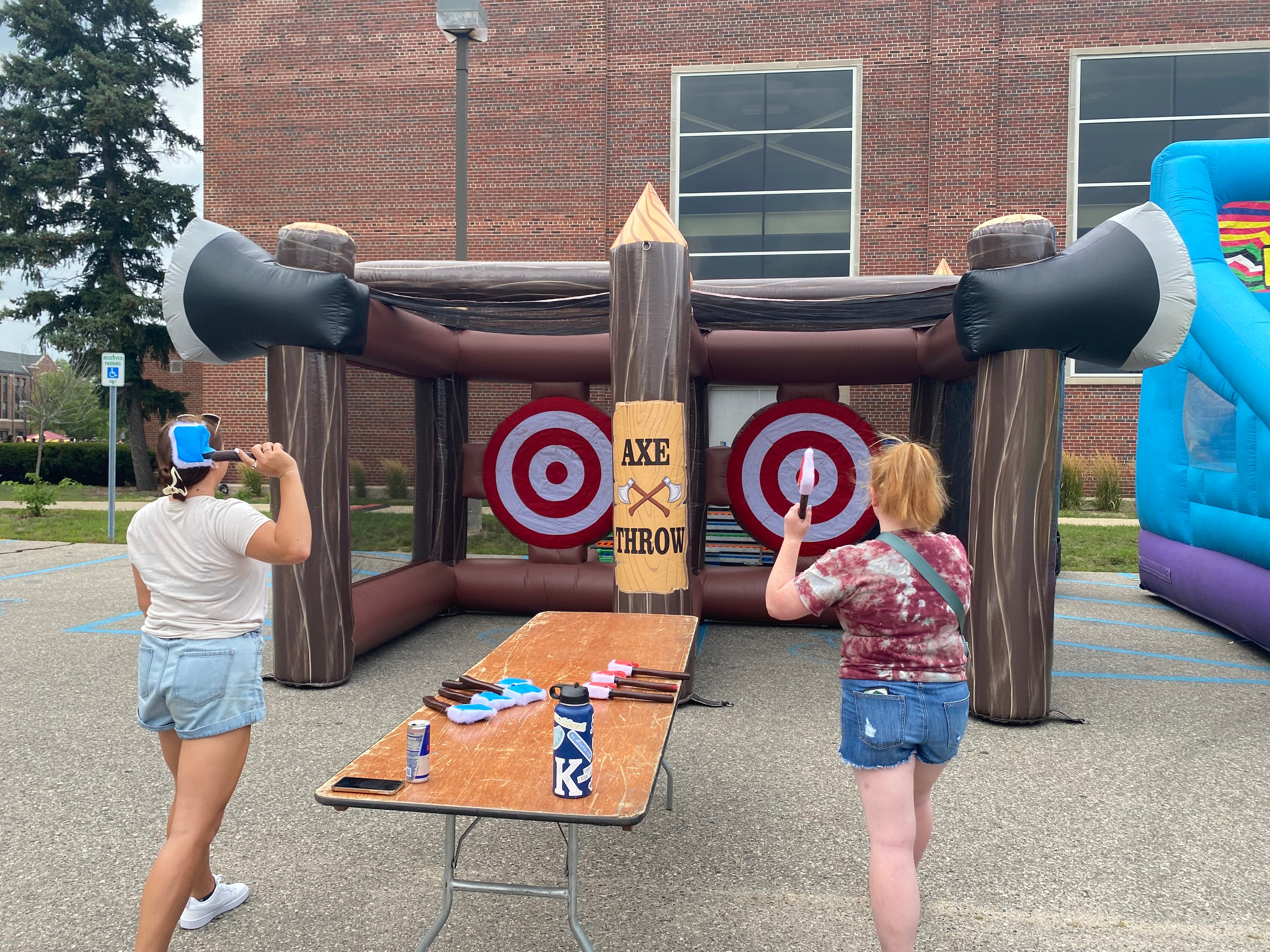 Two guests playing inflatable axe throwing at an outdoor event
