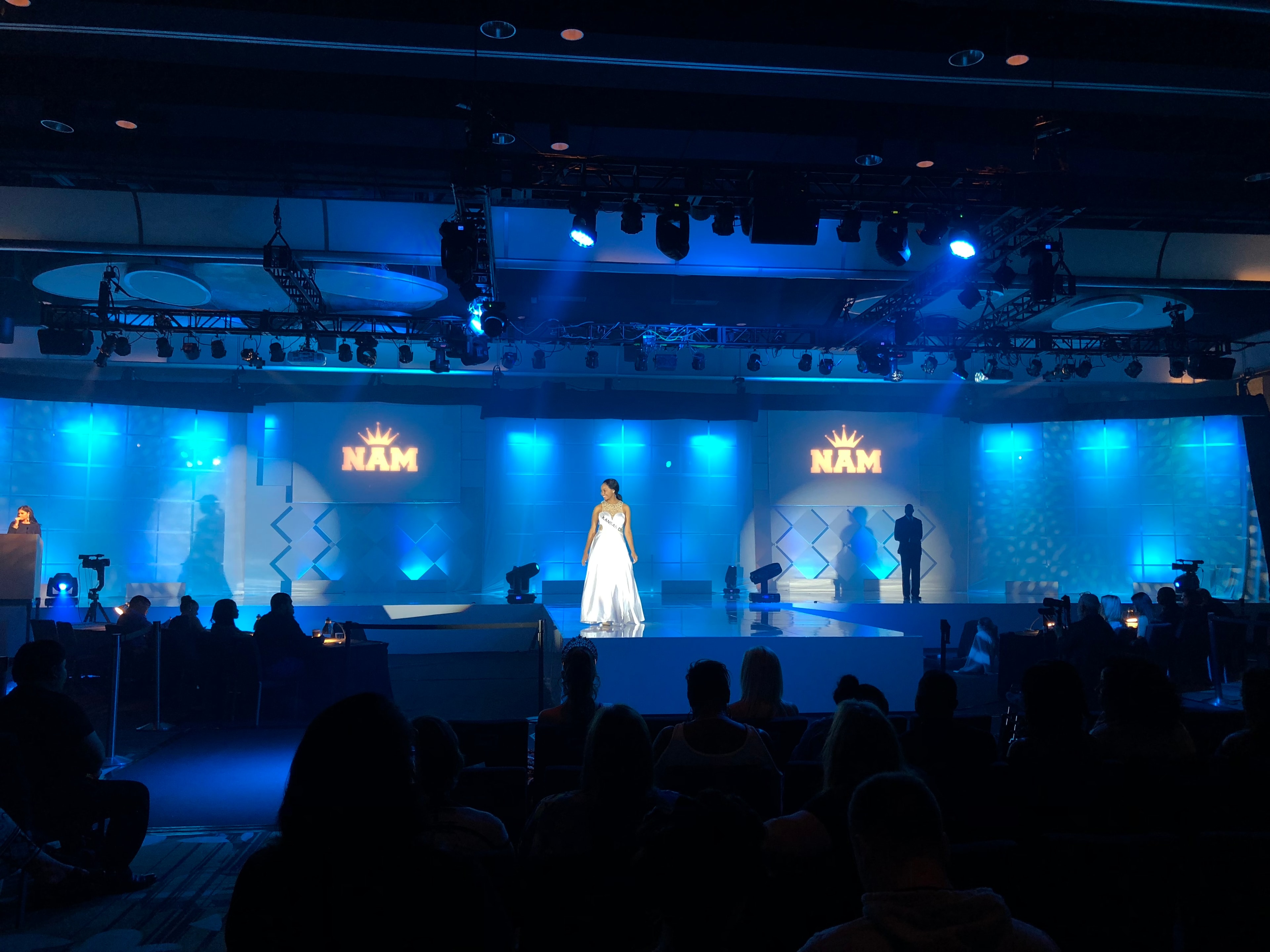 NAM pageant performer on stage with blue lighting and professional production